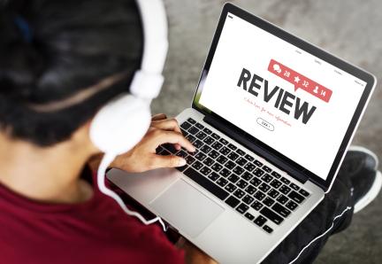 Person sitting with a laptop showing the word "review" on screen